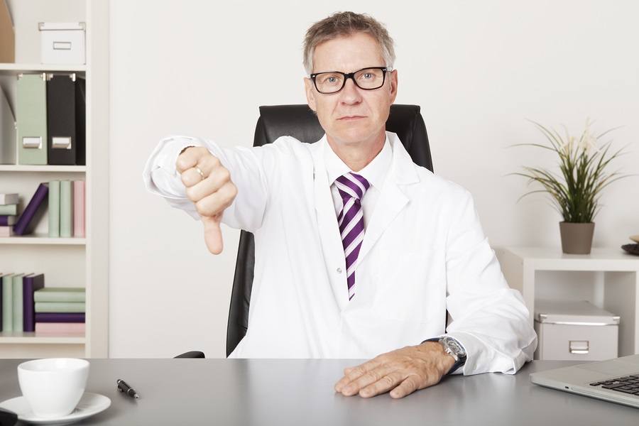 Sad Male Doctor Showing Thumbs Down Emphasizing Unsuccessful Result