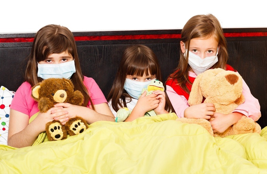 Sick children in bed wearing medical masks because of infection with influenza virus.