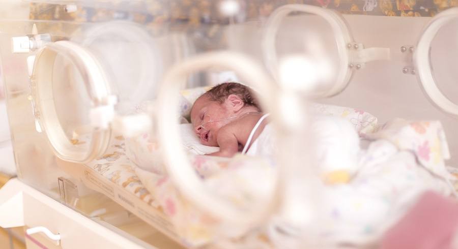 Premature newborn baby girl in the hospital incubator after c-section in 33 week