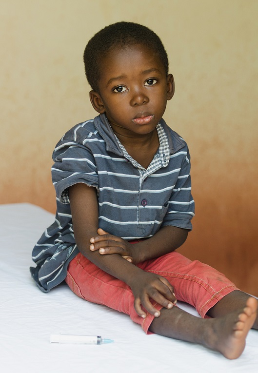 Little boy sitting in a hospital in Africa waiting to get an injection.