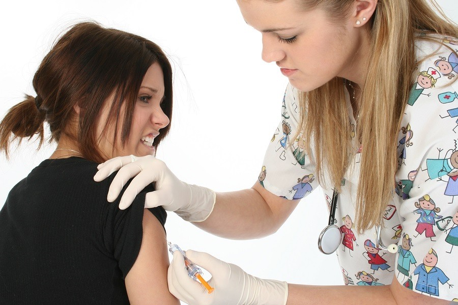 Teen girl afraid of needles getting a shot.