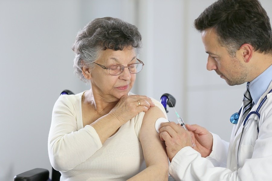 Doctor giving vaccine injection to elderly woman