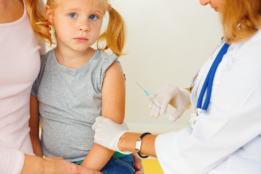 This is a photograph of Doctor vaccinating small redhead girl.