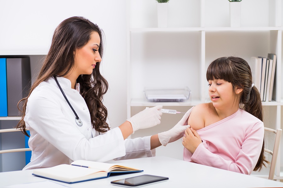 Female doctor giving injection to a scared little girl without parents present.