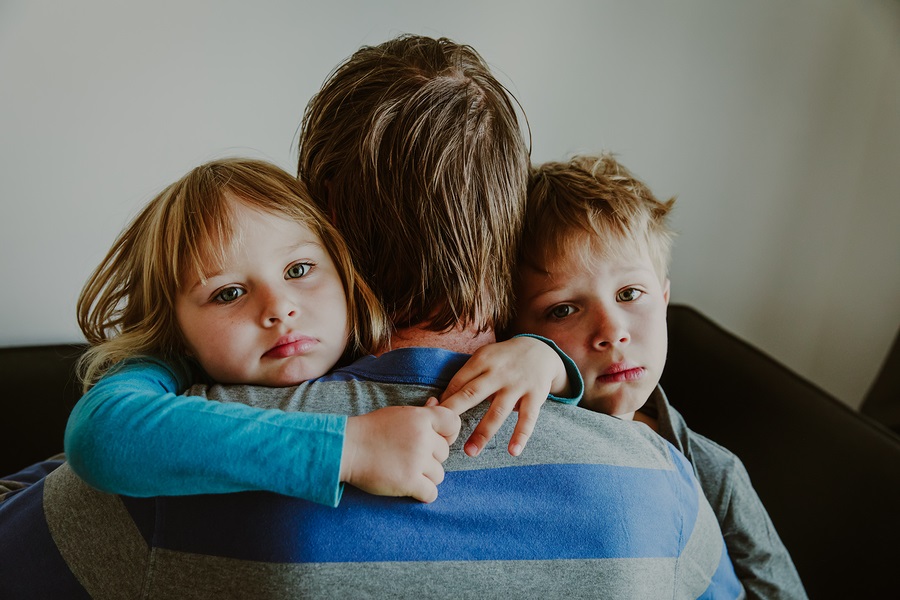 Sad children hugging father at home photo.