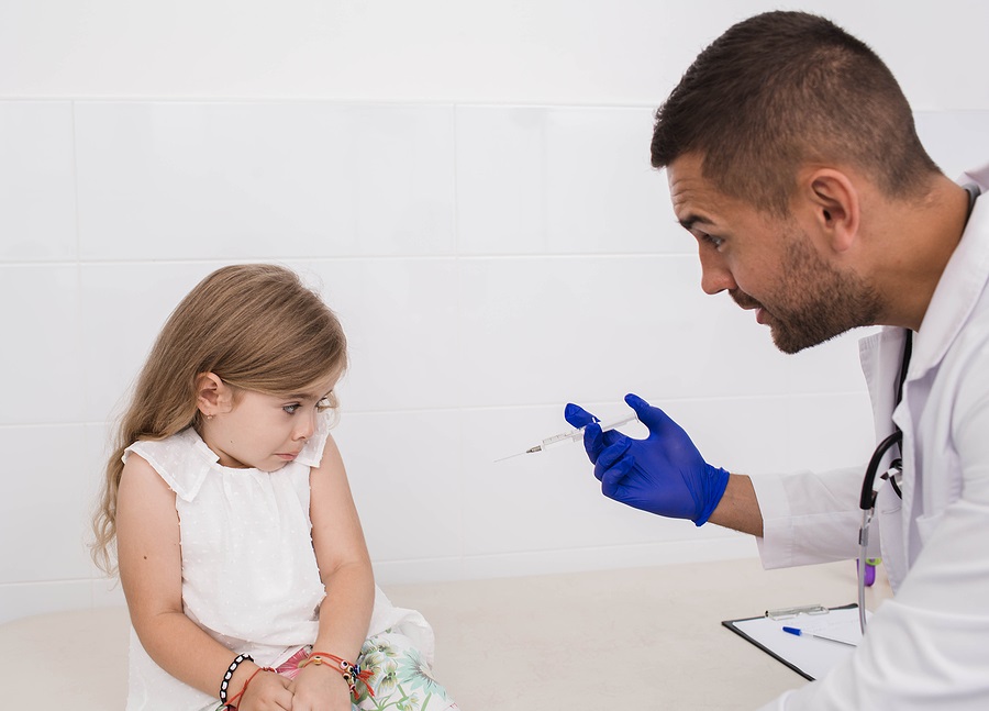 little girl is afraid of vaccination. Doctor with a syringe and a scared child