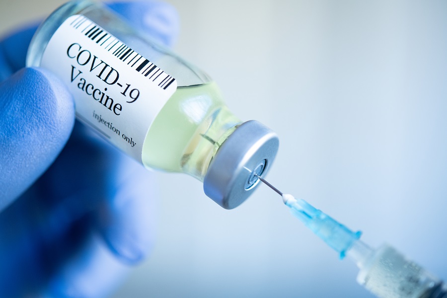 Medico che estrae il vaccino Covid-19 dal flacone di fiala e riempie l'iniezione di siringa per la vaccinazione.